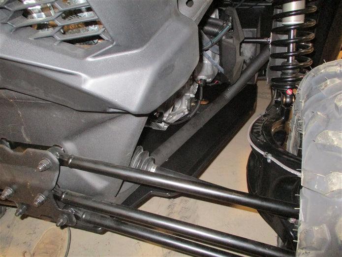 Close-up view of an off-road vehicle's rear suspension, drivetrain and axle components with visible shocks and control arms