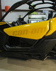 Side view of a yellow and black Can-Am Maverick X3 off-road vehicle parked indoors