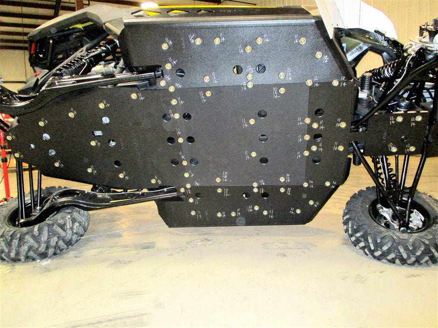 Underside view of an off-road vehicle showing a custom skid plate with multiple bolts and labeled markings