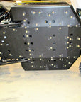 Underside view of an off-road vehicle showing a custom skid plate with multiple bolts and labeled markings