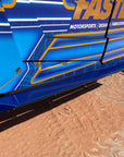 Close-up of blue rock slider steps on a FastLab-branded off-road vehicle parked on red dirt.