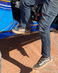 Person using blue rock slider steps to enter an off-road vehicle on a dirt trail.