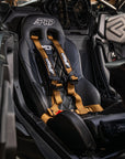 PRP seat with harness installed in a Can-Am vehicle, featuring black upholstery and tan safety straps